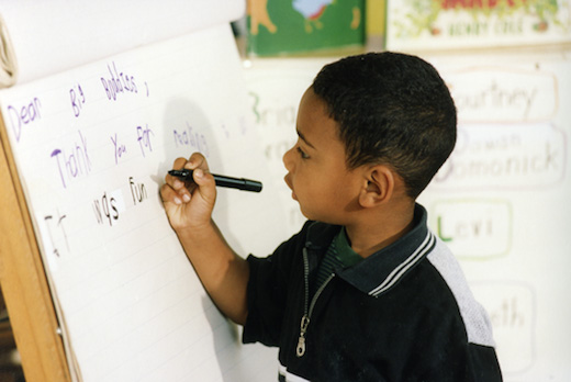 Young child writing on chart paper